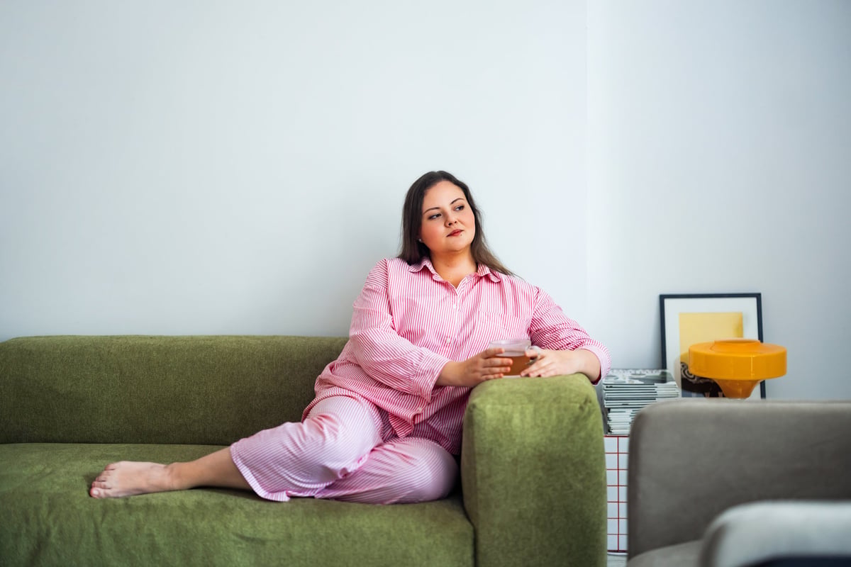 A serene individual in cozy loungewear enjoys a peaceful moment on a sofa