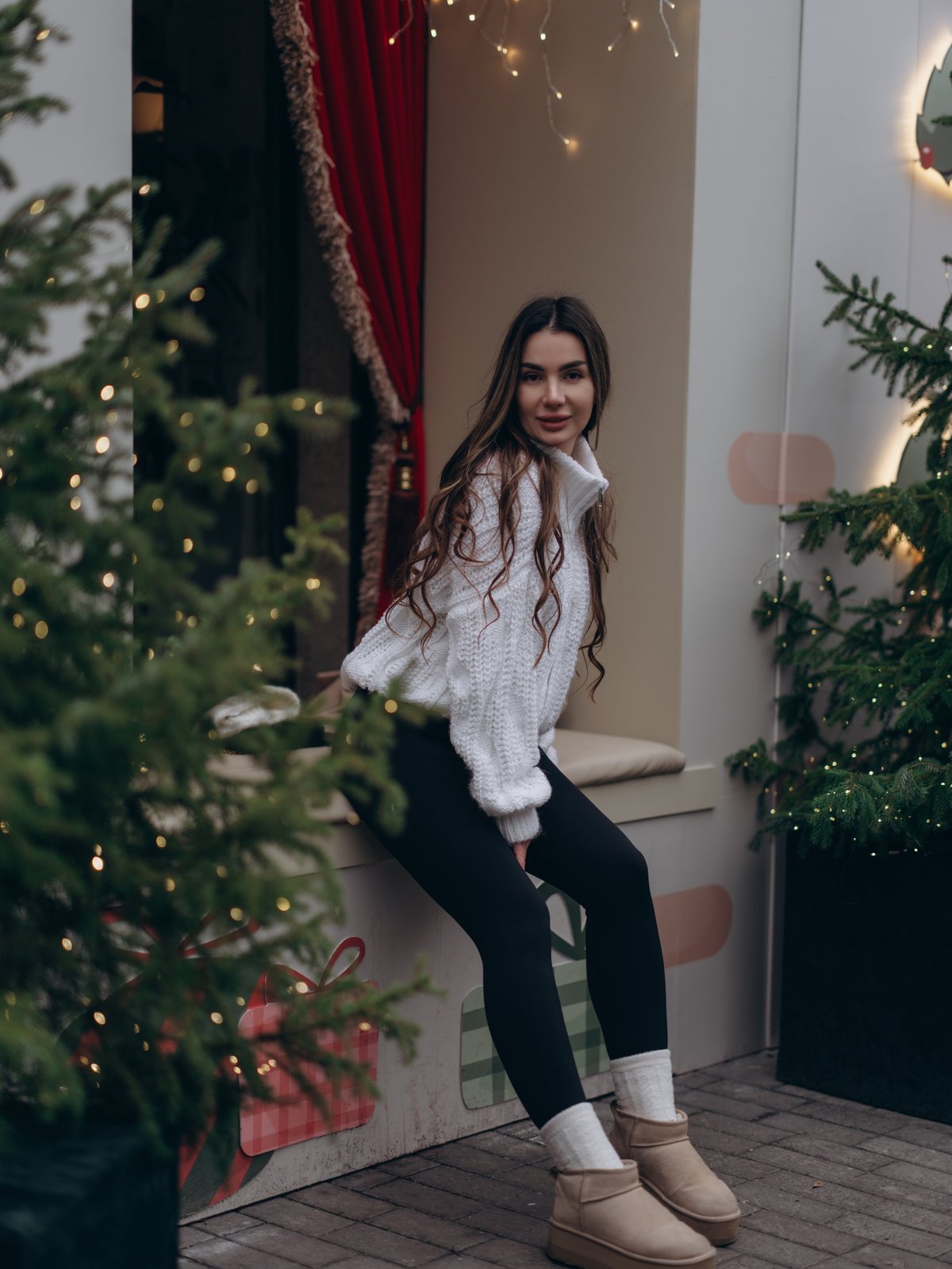 Happy young woman wearing white knitted sweater and black leggings