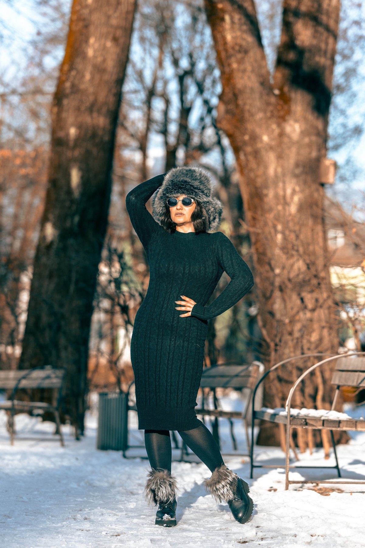 Female model in black knitted dress in snowy park
