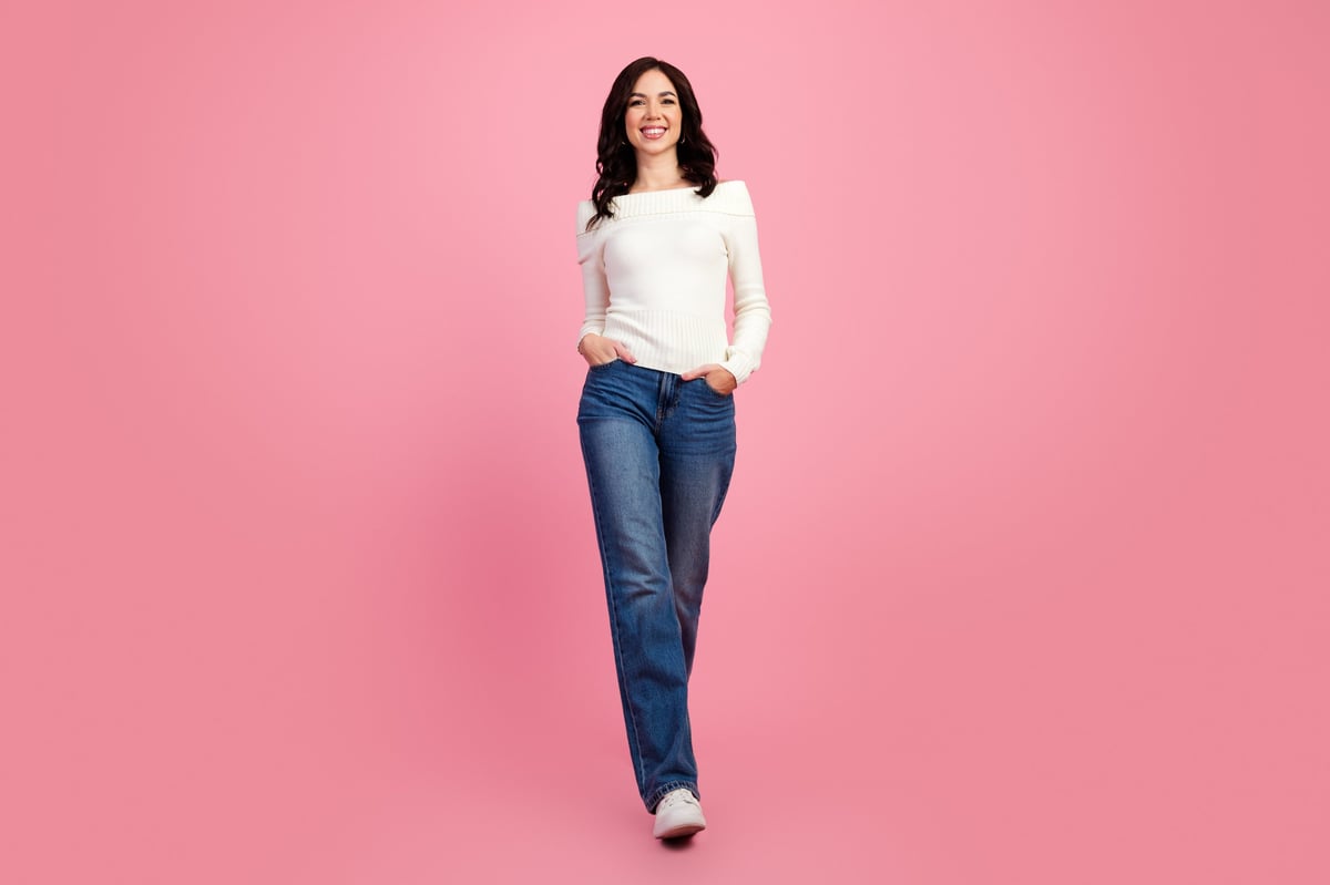 Smiling woman in blue jeans and white off-shoulder sweater