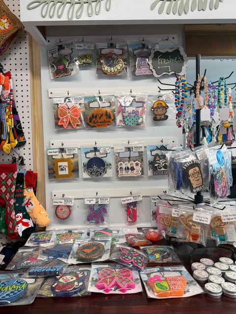 Retail display shelf with Halloween and decorative items including ornaments, keychains, and accessories organized in clear containers